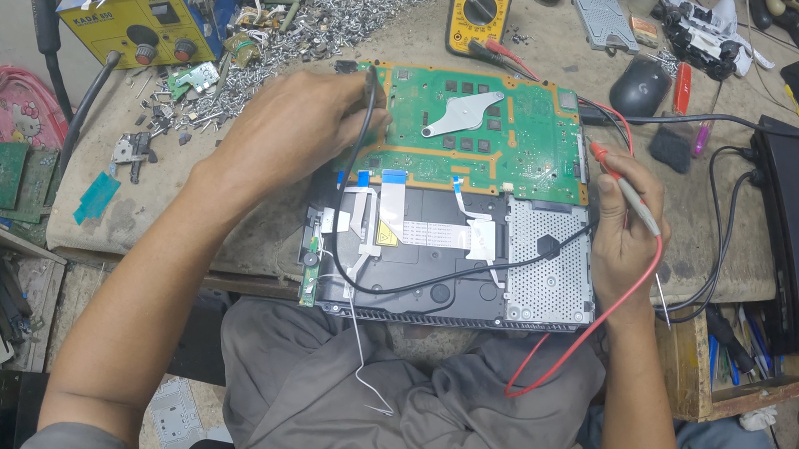 A technician testing an exposed game console circuit board